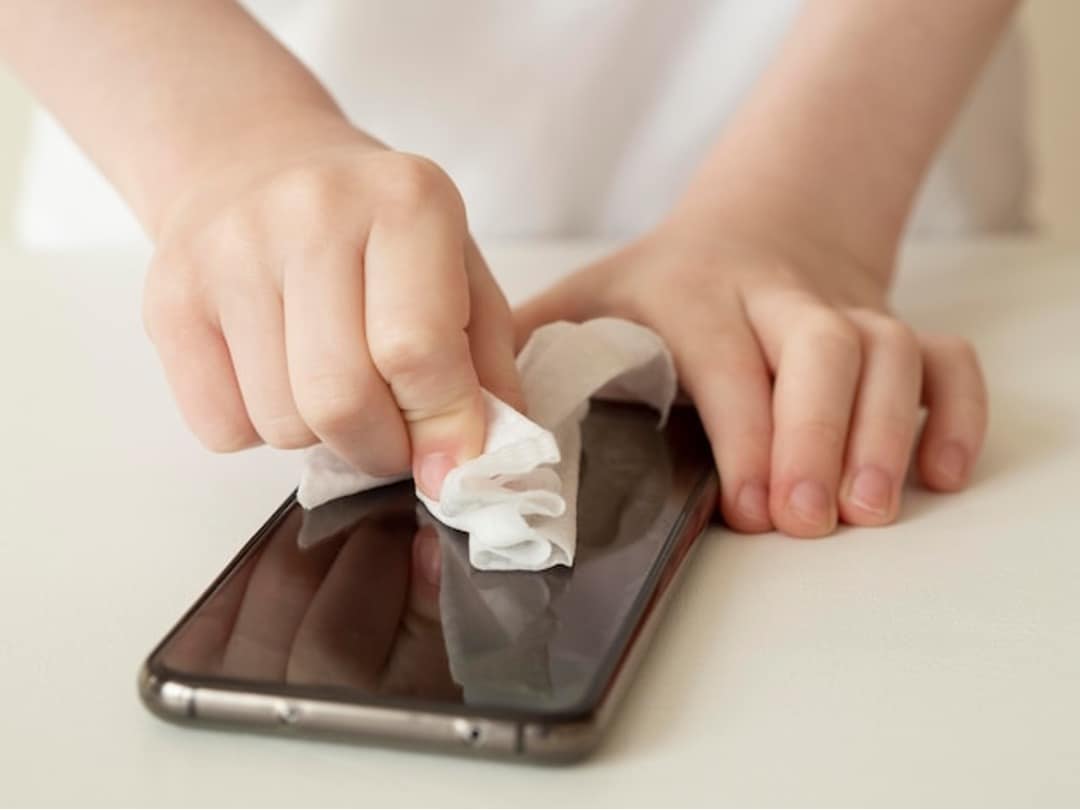 person wiping phone with paper towel